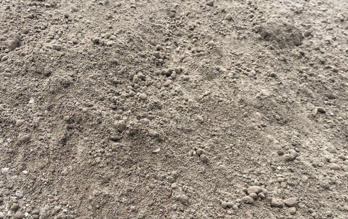 A pile of three-quarter minus road base, grey-brown and full of fines, ready to compact