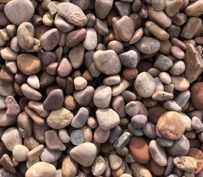 Amethyst rock spread out, rounded pebbles mixing plum, purple, tan and grey, with a coin for scale