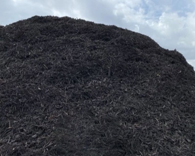 A long mound of black dyed mulch under an open sky