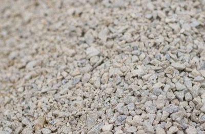 Chipped pea gravel, small angular pale stone spread flat across the ground