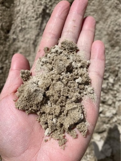 A hand holding crusher fines, fine grey grit that packs down smooth underfoot, what Utah sells in place of decomposed granite