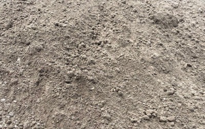 A pile of three-quarter minus road base, grey-brown and full of fines, ready to compact
